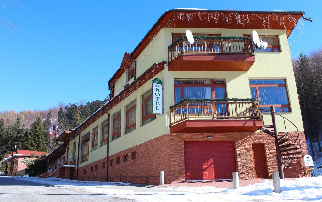 DrienicaHotel Šomka的一座在雪中设有两个阳台的建筑