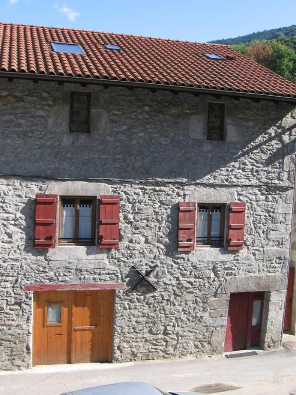 莱萨卡Larraenea Bed and Breakfast的一座石头建筑,上面有红色百叶窗