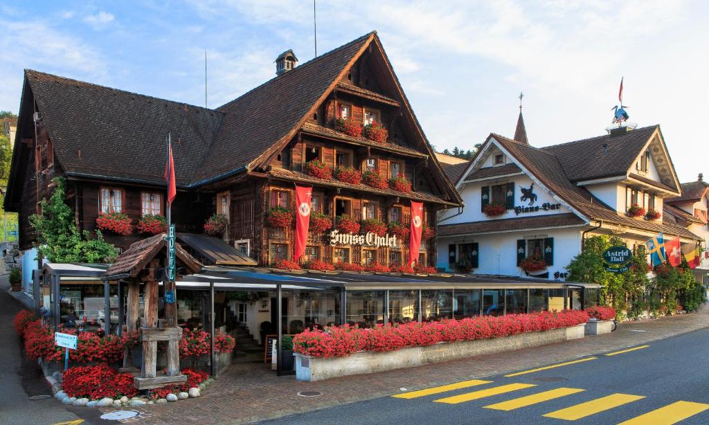屈斯纳赫特Swiss-Chalet Merlischachen - Historik Chalet-Hotel Lodge的一座大型的木质建筑,前面有鲜花