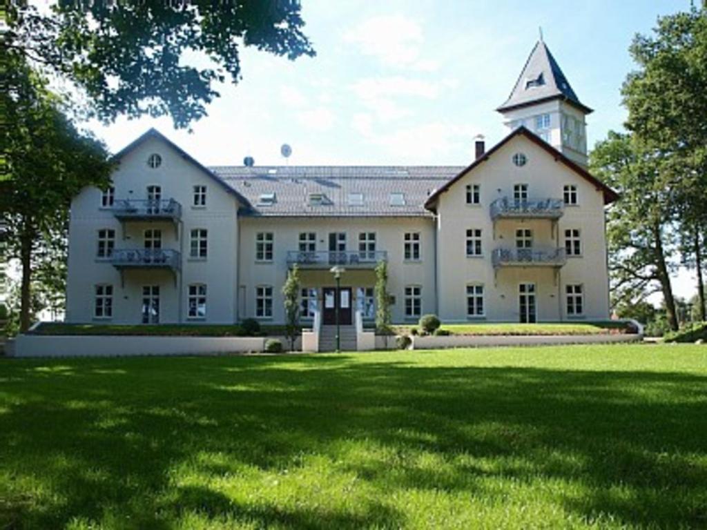 霍恩宁多夫Appartement Schloß - Hohen Niendorf的前面有草地的大型白色建筑