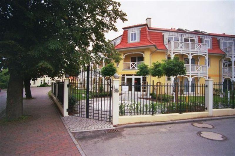 奥斯赛拜-屈隆斯博恩Appartmenthaus Ostseestrand的前面有栅栏的黄色房子
