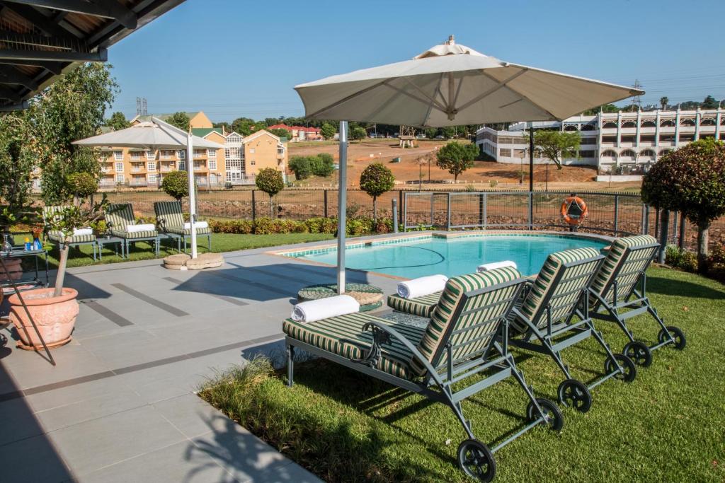 约翰内斯堡City Lodge Hotel Eastgate的游泳池旁的一对椅子和一把遮阳伞