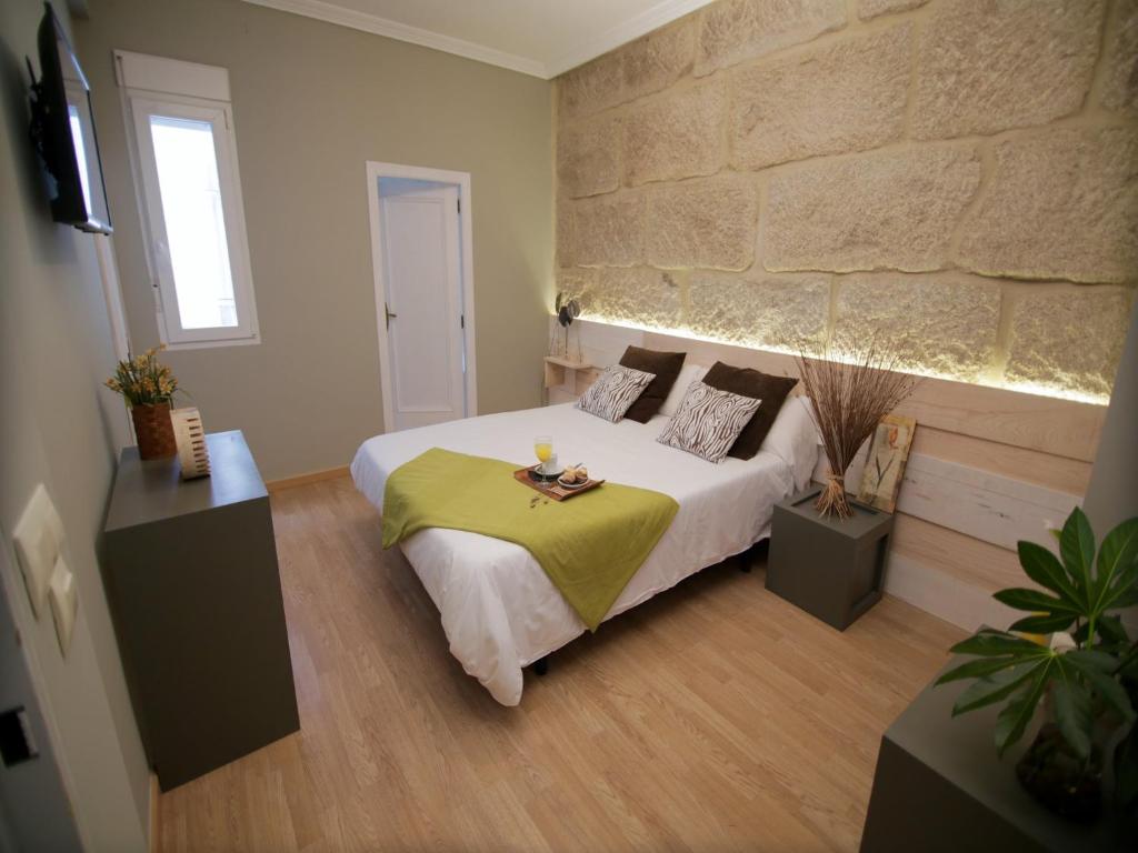 维戈Hotel Alda Estación Vigo的一间卧室设有一张床和石墙
