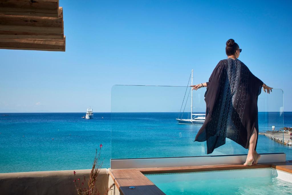 普拉迪斯亚罗斯Kosmoplaz Beach Hotel的站在游泳池边望着大海的女人