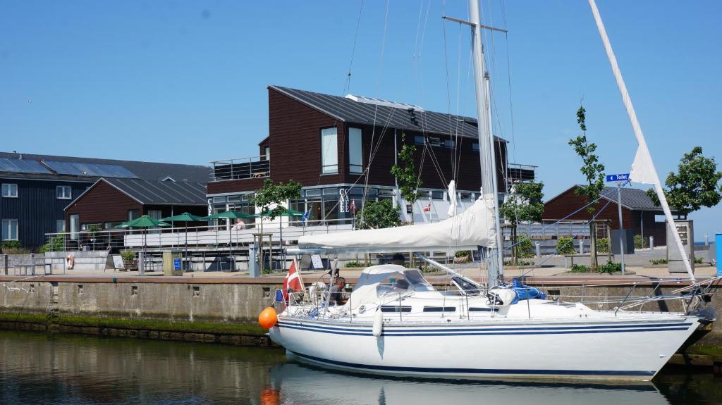 博恩瑟隆德酒店的一艘白色帆船停靠在港口,有房子