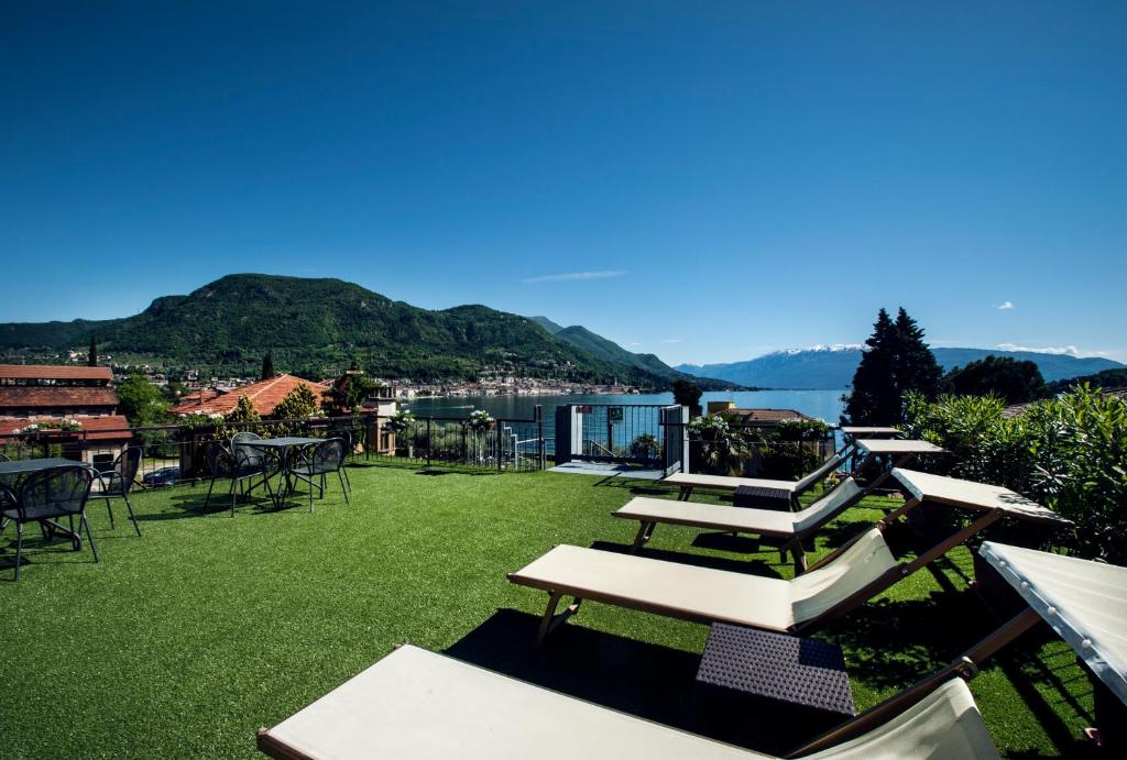 萨罗Hotel Conca d'Oro的草坪上一排桌子和椅子,上面有湖泊