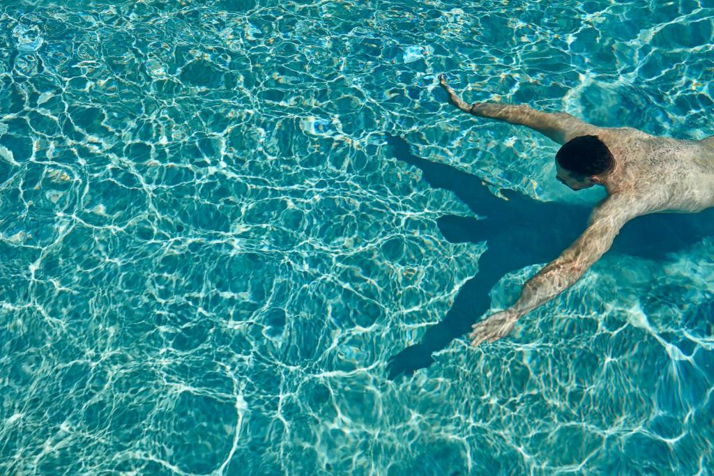 奥诺斯米科诺斯波浪海滨公寓式酒店的一个人在水中游泳