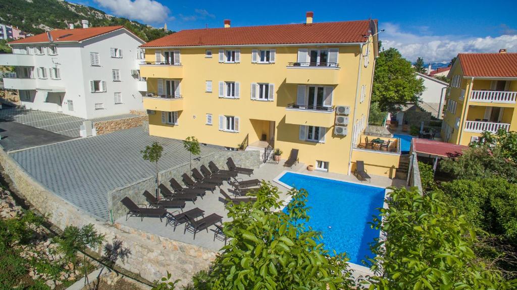 巴斯卡Apartments Gorica 2的一座黄色的大建筑,设有游泳池和椅子