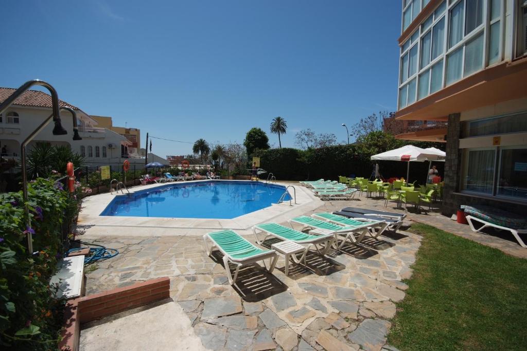 贝纳尔马德纳朵拉玛公寓酒店的一座带躺椅的游泳池位于大楼旁
