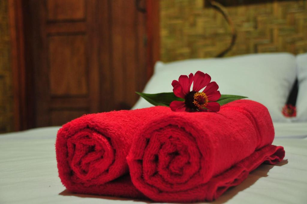特特巴图绿岛民宿的床上的红色毛巾,上面有花
