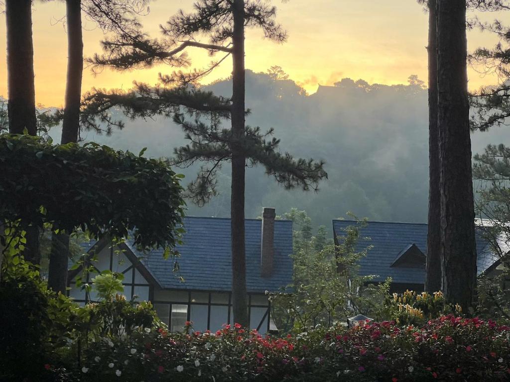 大叻Lan Anh Villas Resort的有蓝色屋顶和树木和鲜花的房子