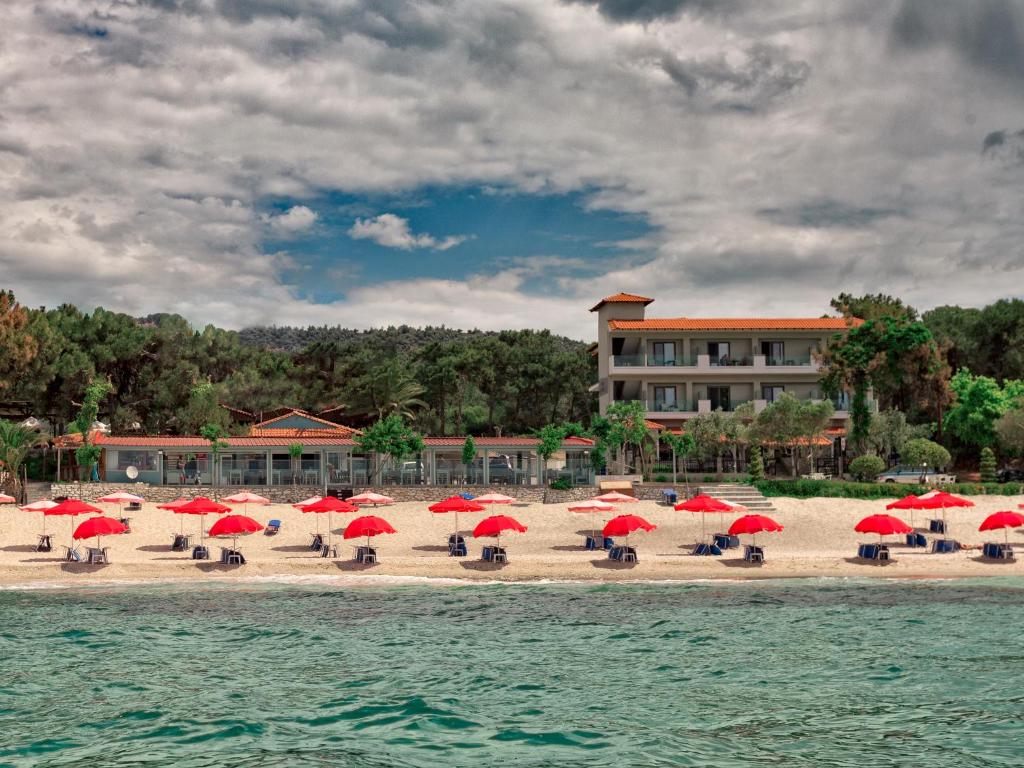 佩弗卡里Hotel Akti的海滩上设有红色遮阳伞和椅子,还有一座建筑