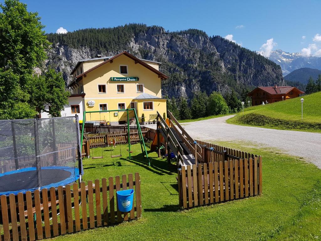 福尔施陶Alpengasthof Draxler的草丛中带围栏和游乐场的房子