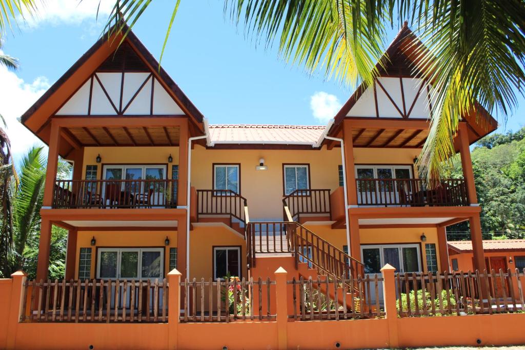 马埃岛贝拉扎尔区绿蓝海滩公寓的前面有棕榈树的房子