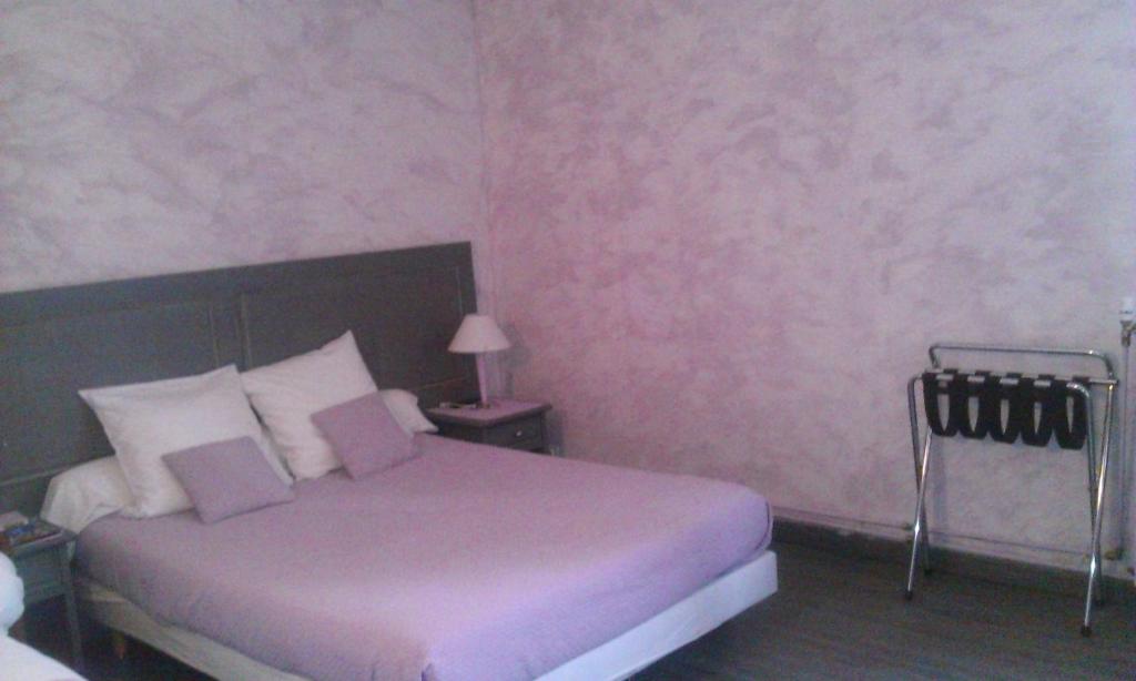 Saint-Pierre-de-Chignac圣皮埃尔“格兰德佩里格”餐厅酒店的一间卧室配有一张床和粉红色的墙壁