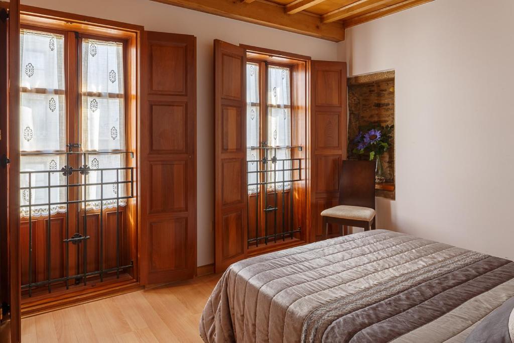 圣地亚哥－德孔波斯特拉Apartamentos Campanas de San Juan的一间卧室设有一张床和两个大窗户
