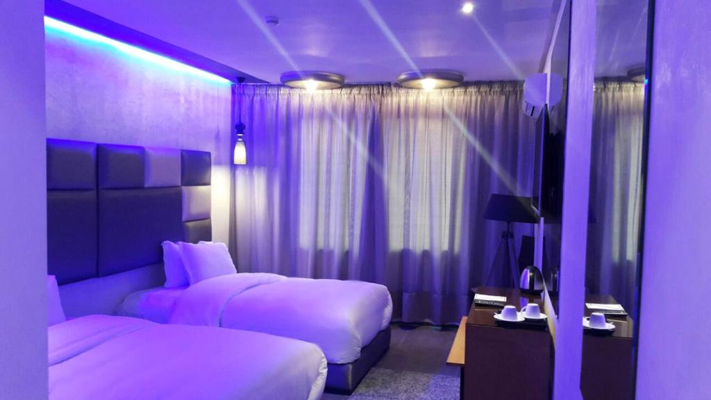 卡萨布兰卡赛文酒店的紫色卧室配有两张床和一张桌子