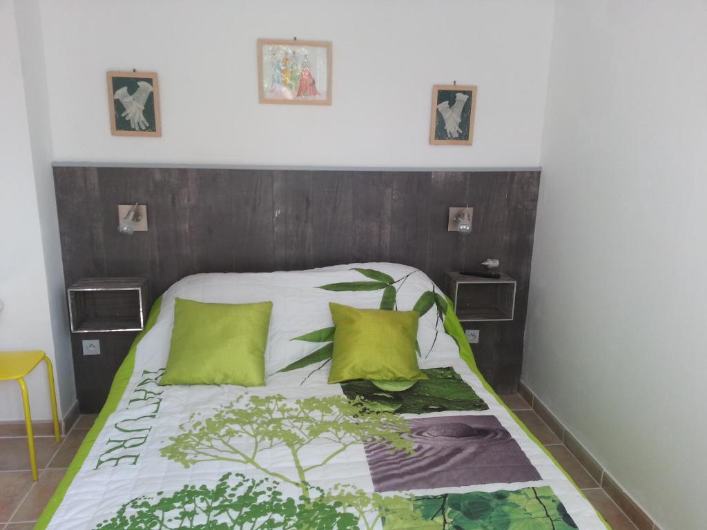 蒙法维伯尔尼与米歇尔住宿加早餐旅馆的一张带木制床头板和两个绿色枕头的床
