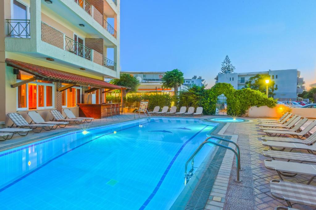 科斯镇帕夫洛斯酒店的一个带躺椅的游泳池和一间酒店