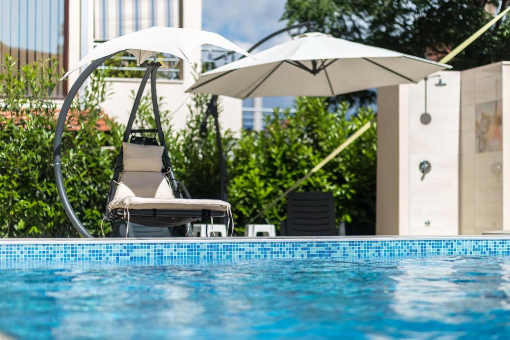 赫尔采格诺维Apartments Rivijera的游泳池旁的椅子和遮阳伞