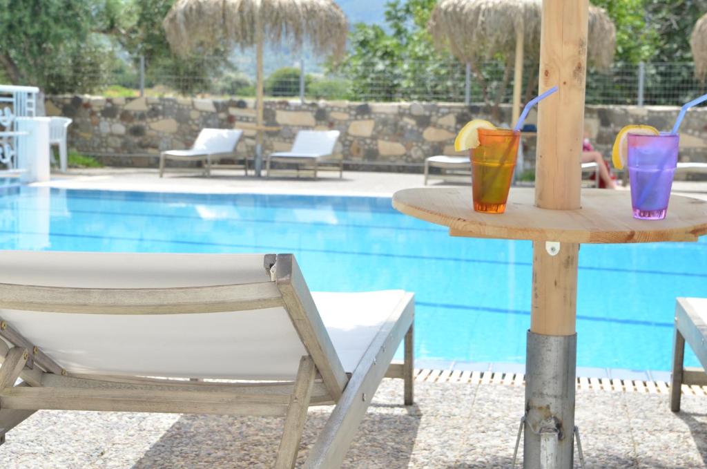 蒂加基蓝巢酒店的一张桌子,旁边是游泳池,上面有两杯饮料