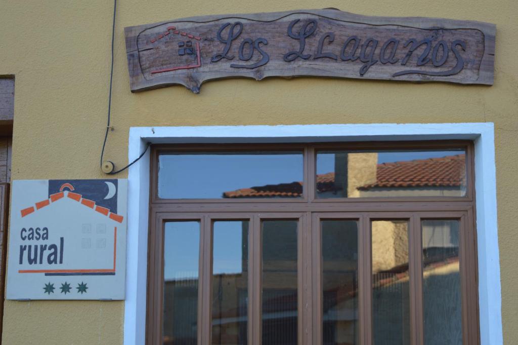 VillaturielCasa Rural Los Lláganos的建筑一侧的标志,带有窗户
