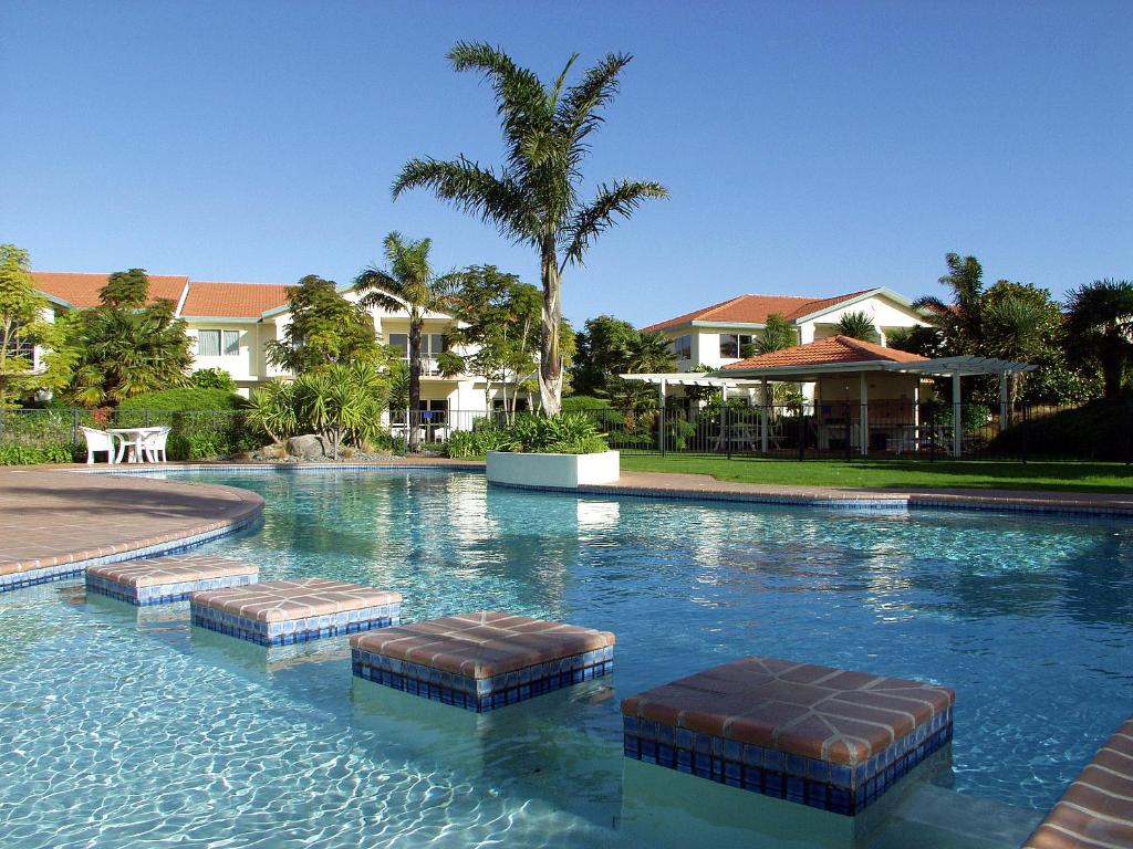 帕帕莫阿太平洋棕榈树度假酒店的一个带两个凳子的游泳池