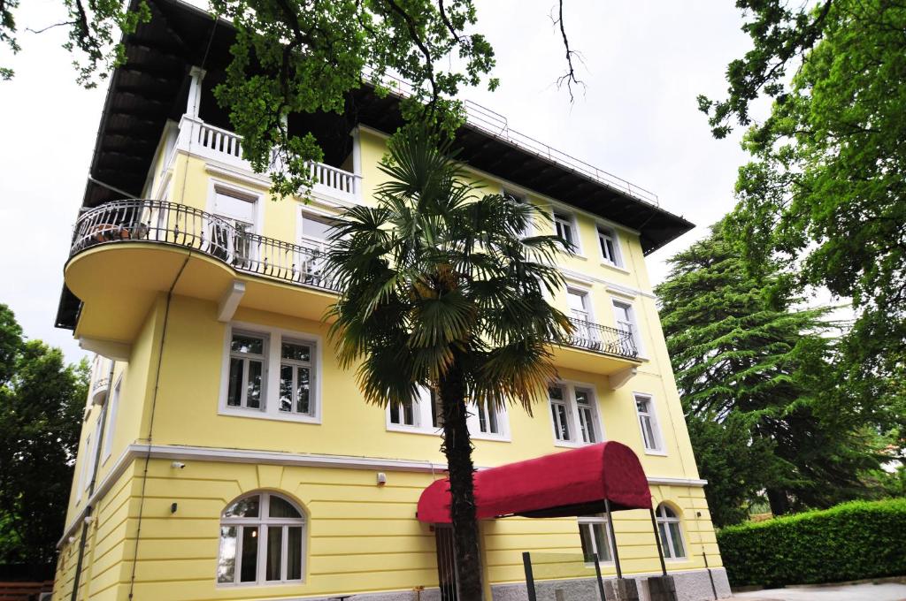 洛夫兰Hotel Villa Laurel的一座黄色房子,前面有一棵棕榈树