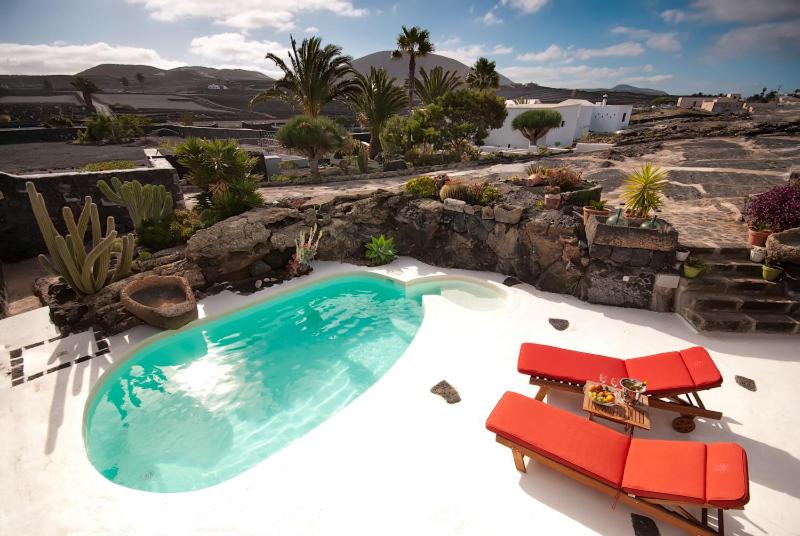 圣巴尔托洛梅Ecofinca La Buganvilla - Adults Only的一个带两把红色椅子的大型游泳池
