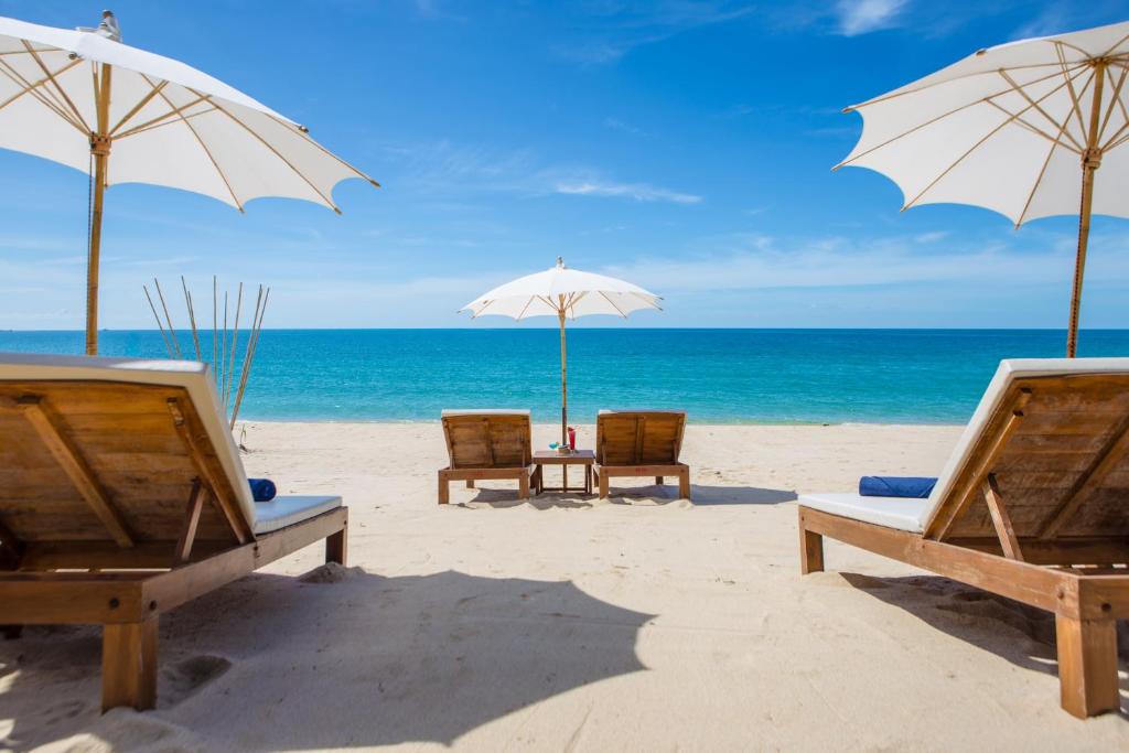 拉迈拉迈椰子海滩度假村的海滩上的2把沙滩椅和遮阳伞