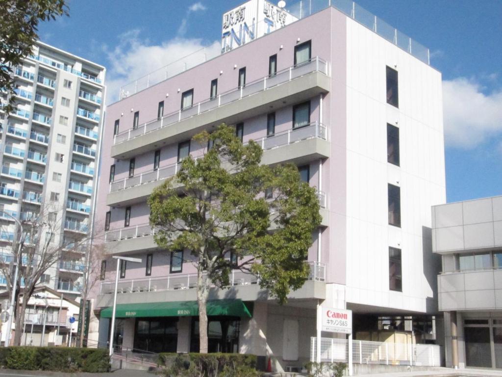 挂川市Hotel Kakegawa Hills的前面有棵树的粉红色建筑