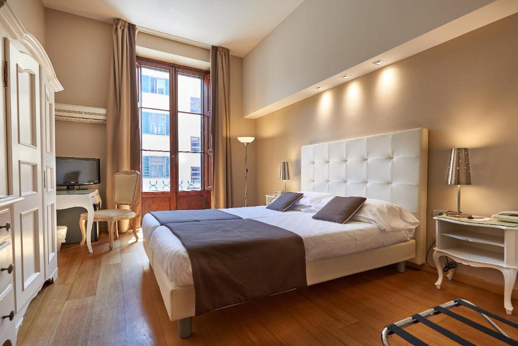 佛罗伦萨科西莫德美第奇酒店的一间大卧室,配有一张大床和一张书桌