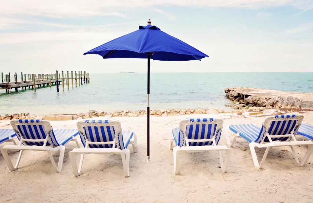 Lower Matecumbe BeachTopsider Resort by Capital Vacations的海滩上的一组椅子和一把遮阳伞