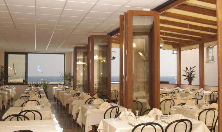 瓦拉泽Hotel Ideale的一间设有白色桌椅的用餐室