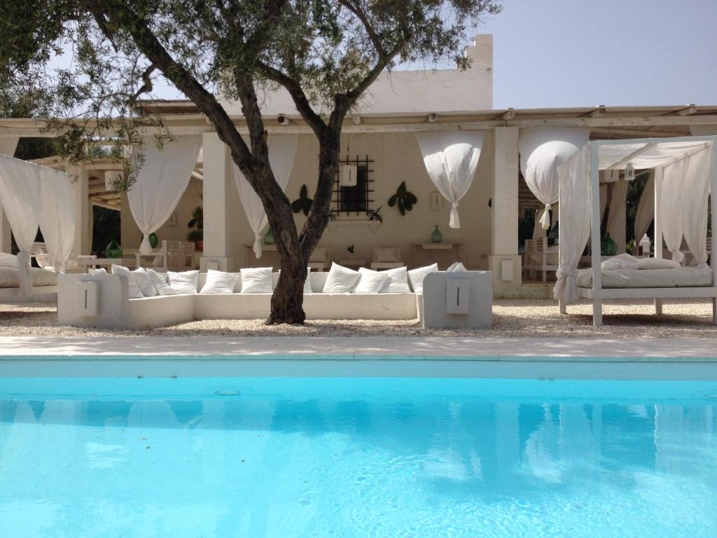 马鲁焦Masseria Scorcialupi的一座带白色沙发的游泳池,一座房子旁边还有一棵树