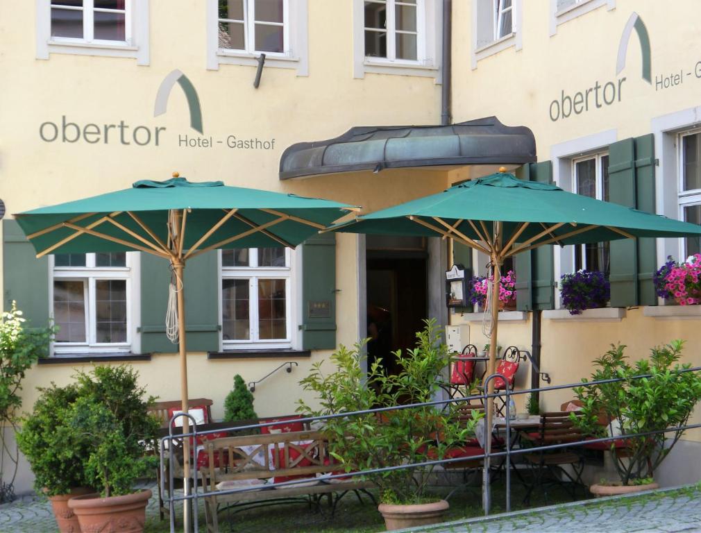 拉芬斯堡奥伯托酒店的大楼前的两张桌子和遮阳伞