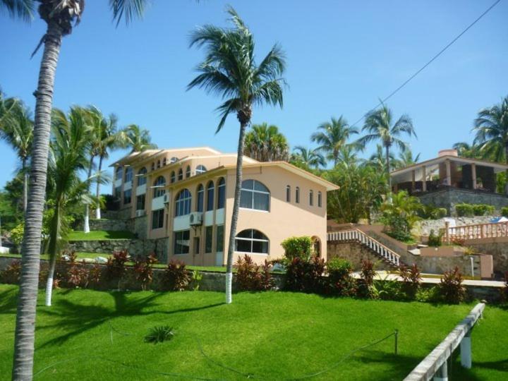 埃斯孔迪多港Hotel Barlovento的一座棕榈树大房子和绿色庭院