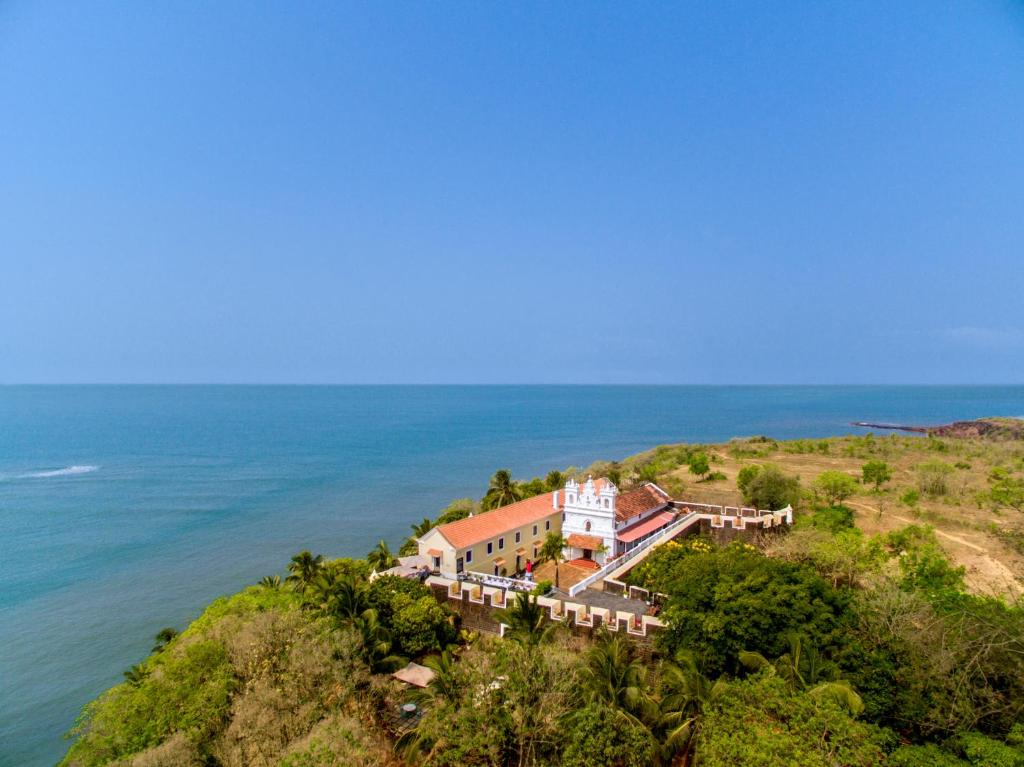 阿姆波尔Fort Tiracol Heritage Hotel的大海旁山丘上房屋的空中景观