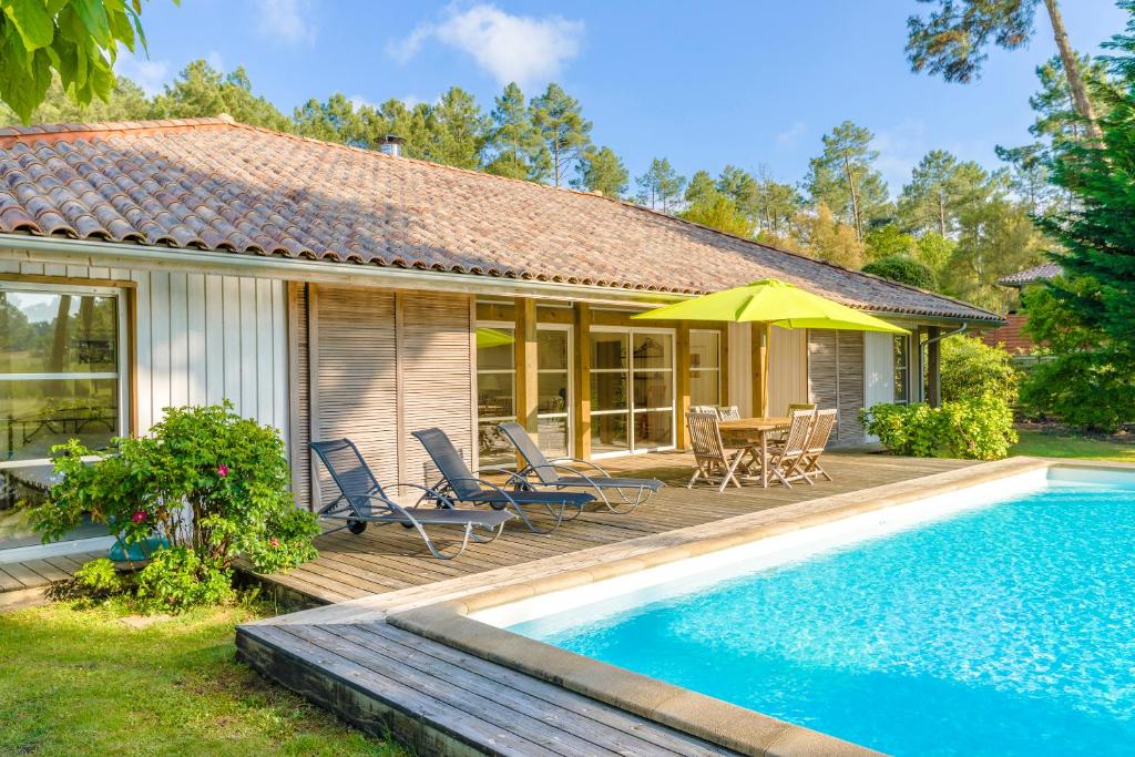莫列马阿Lagrange Vacances La Clairière aux Chevreuils的一座房子,设有游泳池和一个带椅子和遮阳伞的庭院
