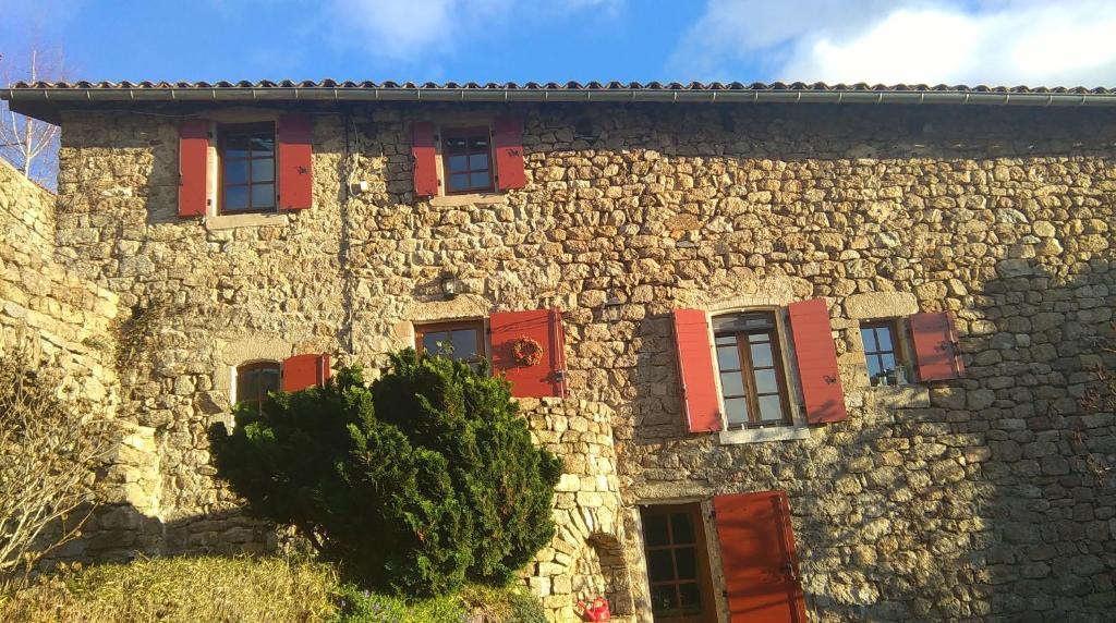 LabouleL'Oustau de Pequeti的一座石头建筑,上面有红色百叶窗