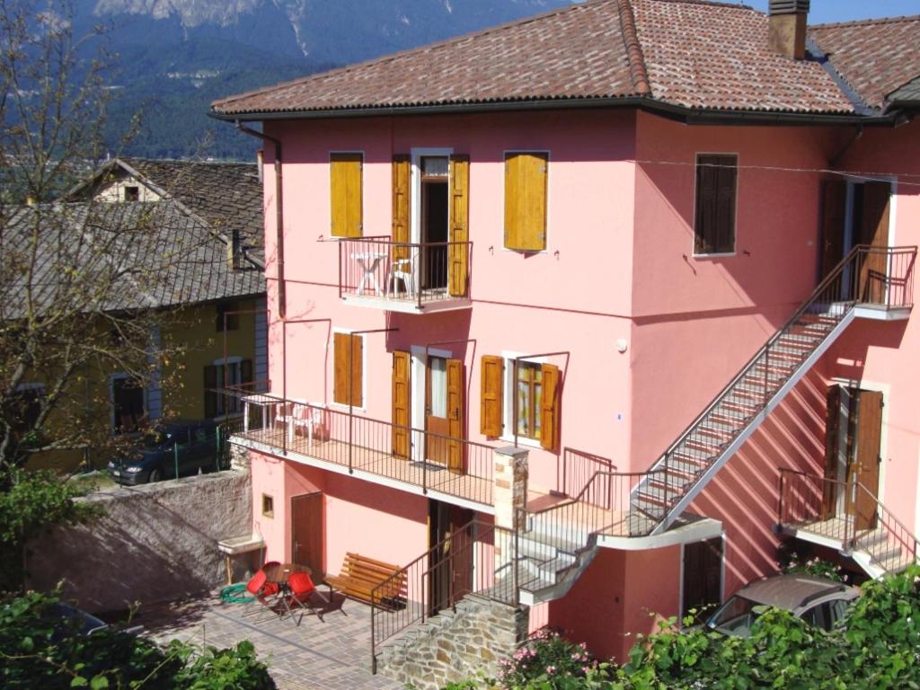 莱维科特尔梅Appartamenti Nadalini的粉红色的房子,设有黄色百叶窗和楼梯