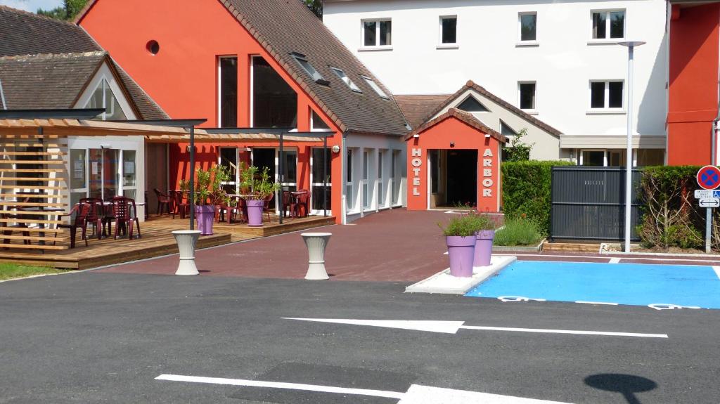 米萨讷Hotel ARBOR - Les Hunaudieres - Le Mans Sud - Mulsanne的一个空的停车场,有房子和一个游泳池