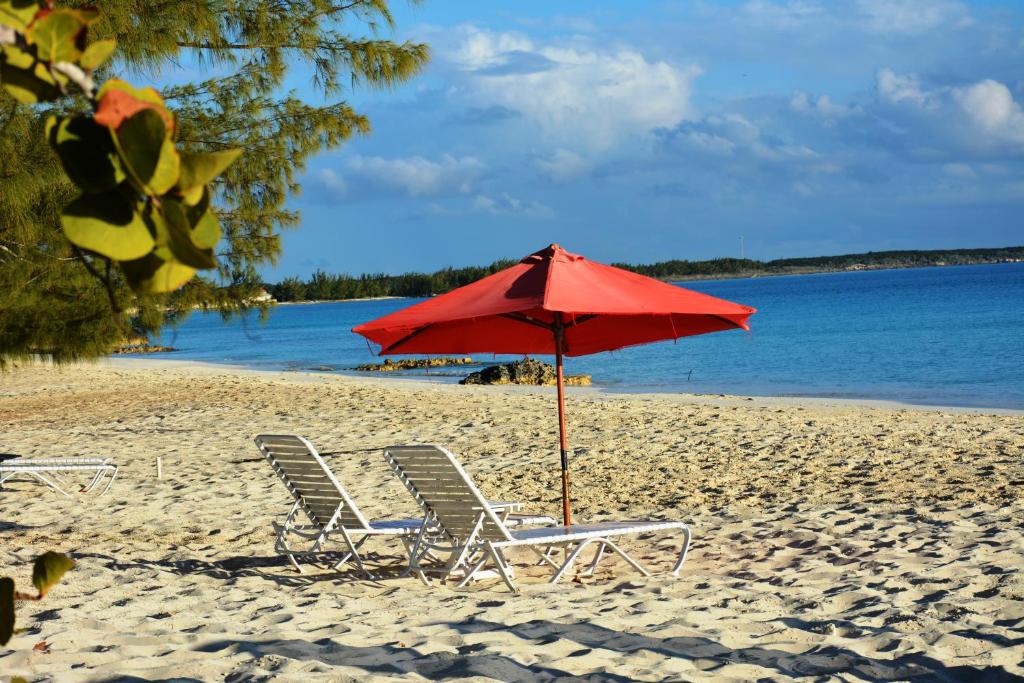 RokerʼsPigeon Cay Beach Club的海滩上的两把椅子和一把遮阳伞