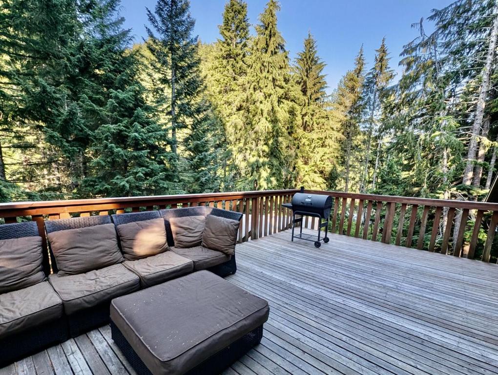 阿什福德Chalet at Rainier Lodge (0.4 miles from the entrance)的一张沙发，放在带烤架的木甲板上