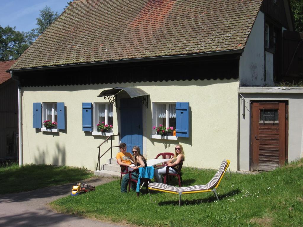 格拉芬豪森霍夫加德伦布农家乐的三人坐在房子前面的草上