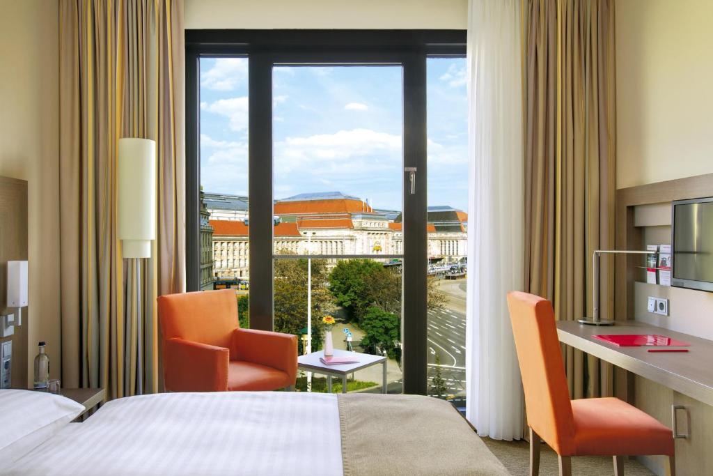 莱比锡莱比锡城际酒店的酒店客房设有一张床、两把椅子和一扇窗户。