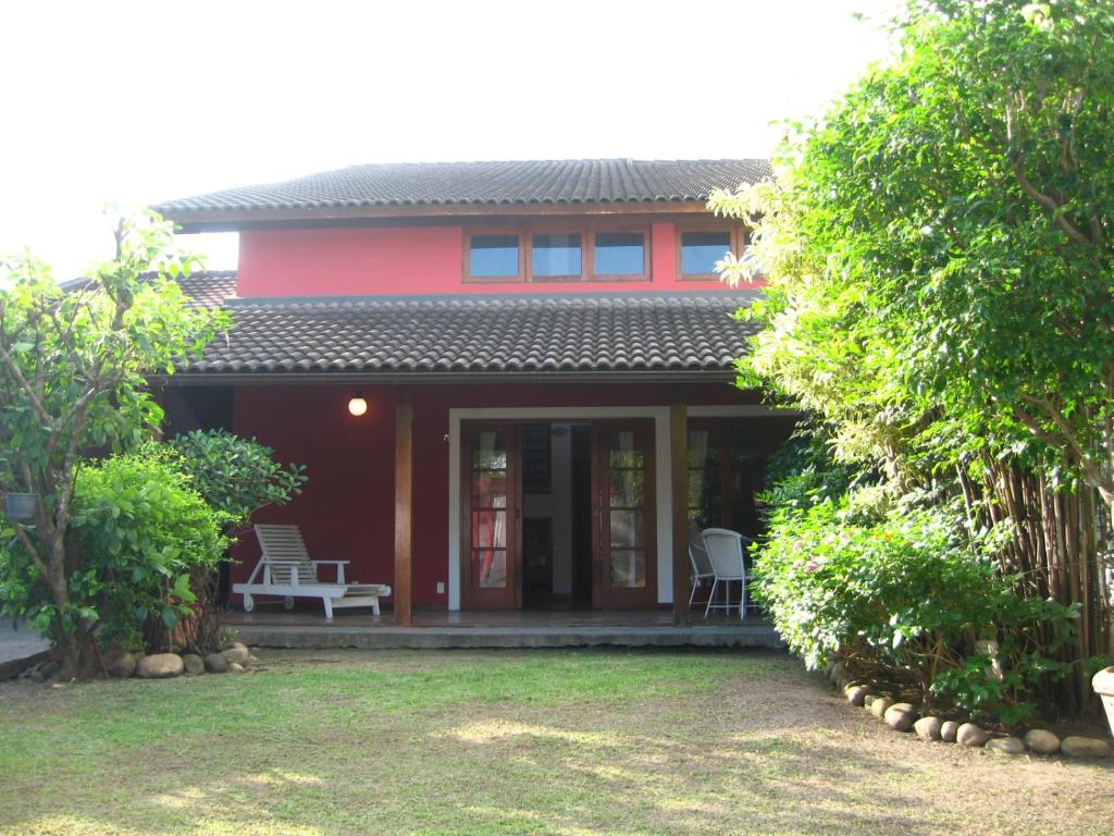 里约热内卢Casa do Sergio的红色的房子,配有两把椅子和门廊