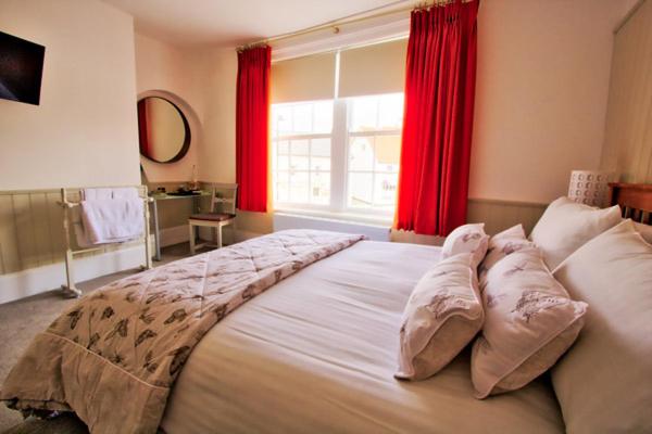 拉姆西帕默斯顿客房住宿加早餐旅馆的一间卧室配有一张带红色窗帘的大床