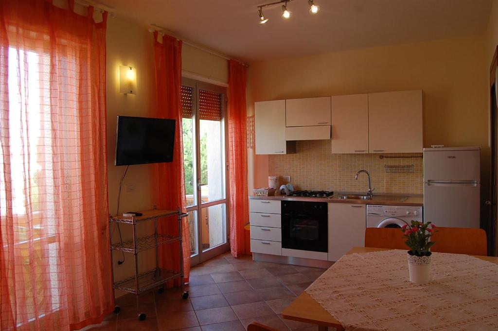 加利波利Tramonto -Appartamenti OltreMare- Lido Conchiglie Gallipoli的厨房配有橙色窗帘和桌子。
