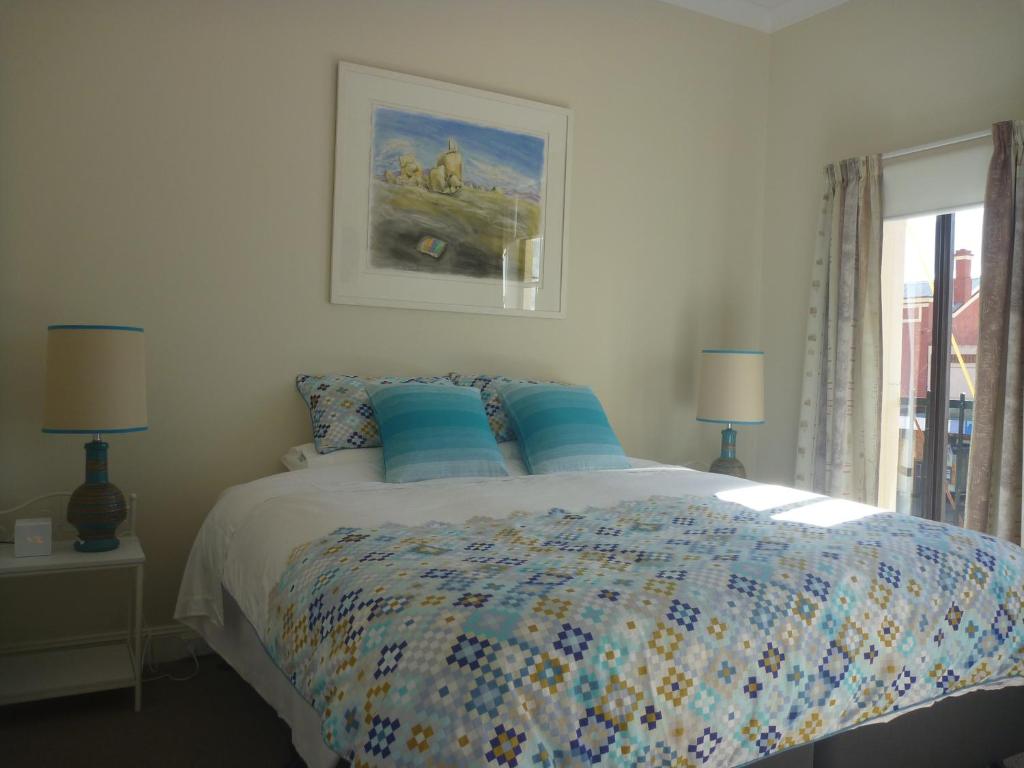 格伦因尼斯昂格里公寓的一间卧室配有一张带蓝色枕头的床和一扇窗户。